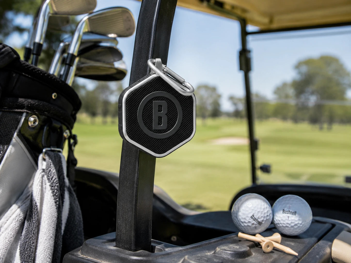 Compact golf GPS speaker clipped to a golf bag